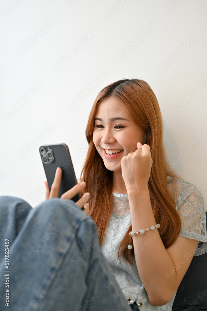 Portrait of a beautiful Asian female relaxes in the living room, using smartphone Portrait of a beautiful Asian female relaxes in the living room, using smartphone