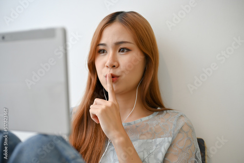 Attractive Asian woman live-streaming on her social media via her digital tablet at home.