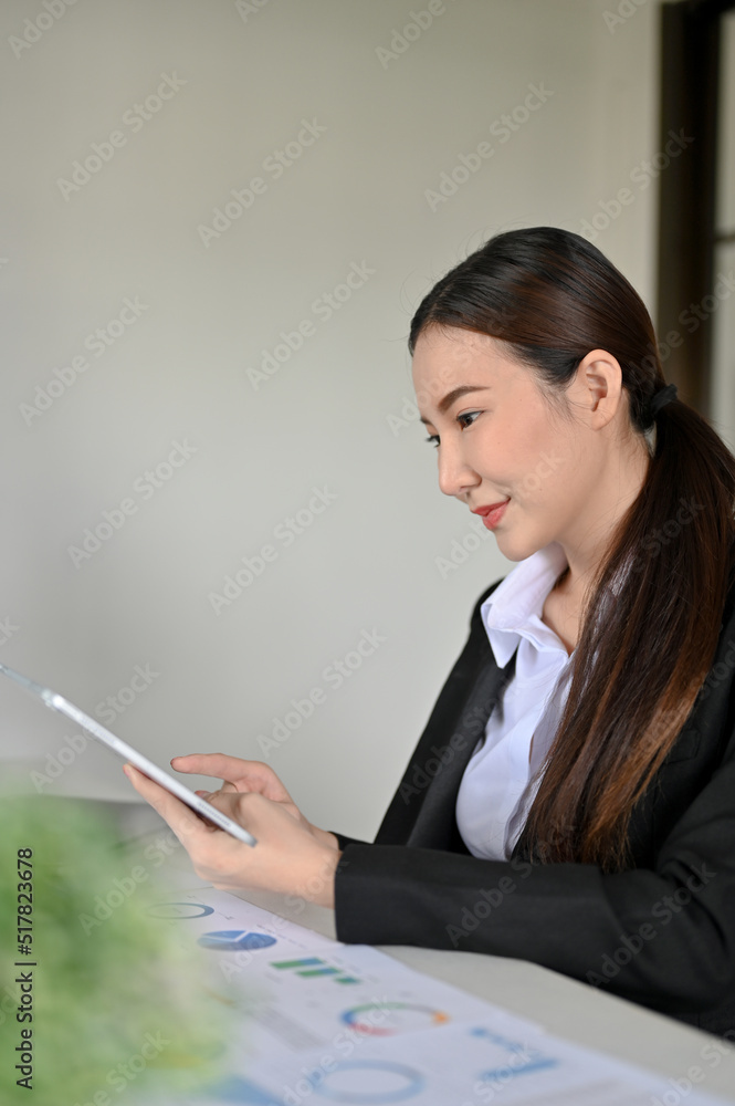 Attractive young Asian businesswoman working on her financial assignment Attractive young Asian businesswoman working on her financial assignment