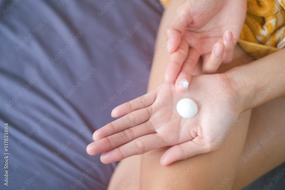 Asia woman sitting on bed and applying cream on her hand. Asia woman sitting on bed and applying cream on her hand.