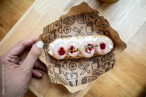 lychee on whipped cream tart plating in a paper plate with a hand grabbing
