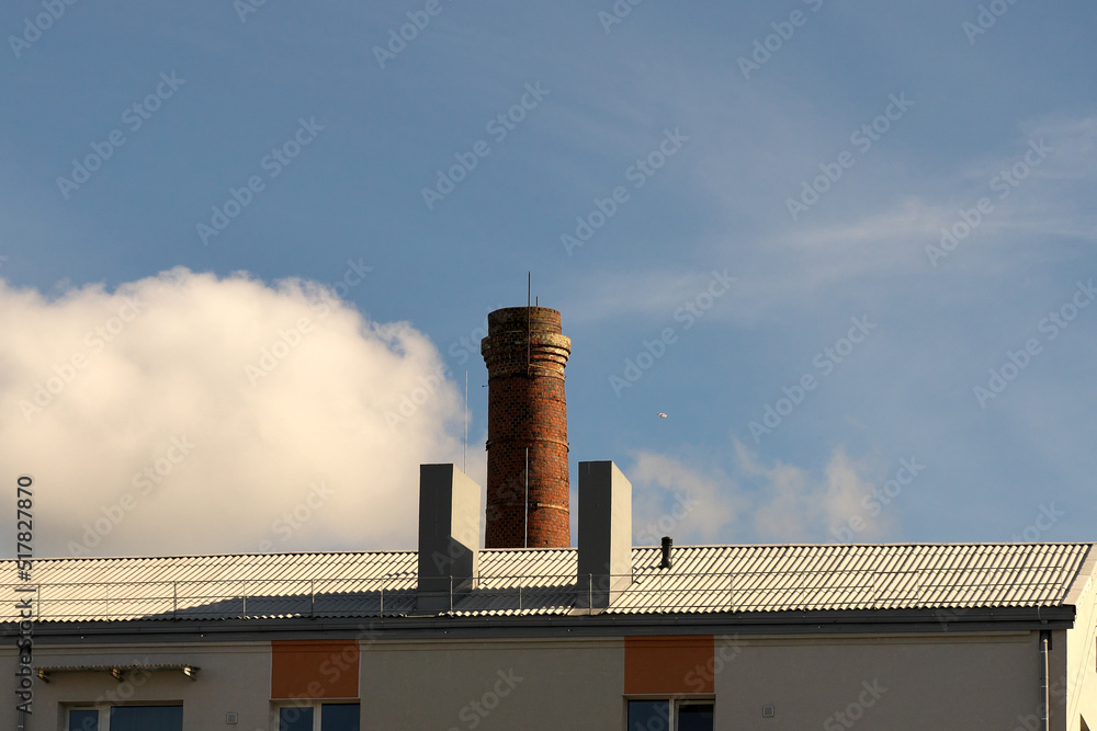 A large brick chimney and two plastered ventilation pipes on the roof of the building.