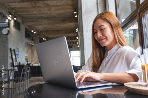 Portrait image of a businesswoman working and typing on laptop computer in cafe