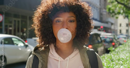 Portrait of a playful tourist blowing bubbles with chewing gum candy. Confident, carefree and happy young female smiling and laughing while having fun in a playful, bubbly and cheerful mood photo