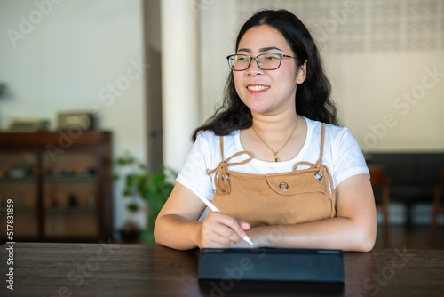 Portrait asian freelance people business female wearing glasses stylish hipste Draw or taking note on digital tablet with electronic pen for browsing internet, chatting and blogging in coffee shop. photo