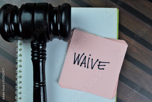 Concept of Waive write on sticky notes with gavel isolated on Wooden Table.