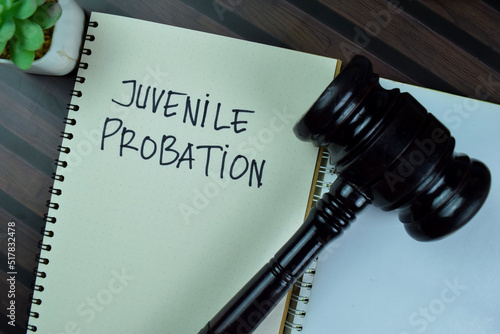 Concept of Juvenile Probation write on a book with gavel isolated on Wooden Table. photo