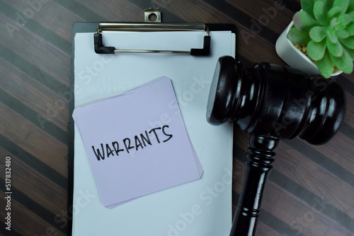 Concept of Warrants write on sticky notes with gavel isolated on Wooden Table. photo