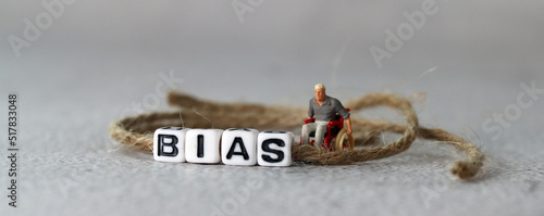 Business concept with white cube arranged in the word ’BIAS' and miniature people. The concept of social prejudice against the disabled. 