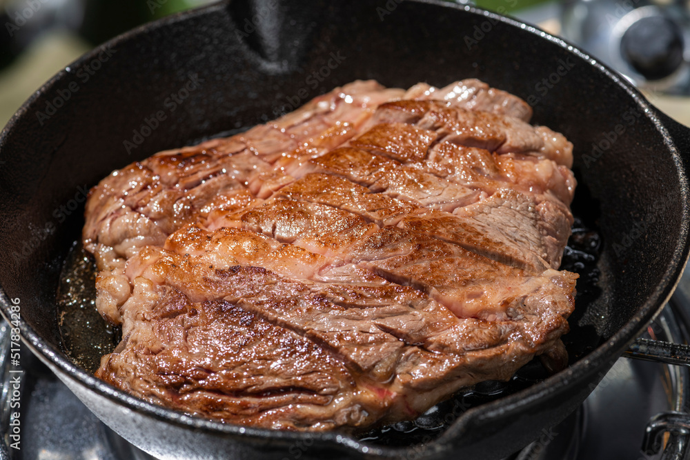 アウトドアのキャンプ場でスキレットを使ってステーキ肉を焼く アウトドアのキャンプ場でスキレットを使ってステーキ肉を焼く