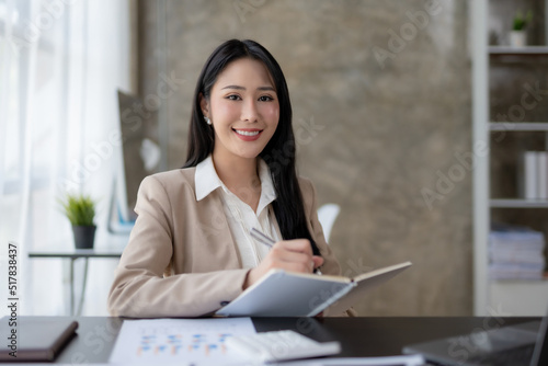 Charming Asian business woman have a happy of working laptop at the office. Looking at camera.