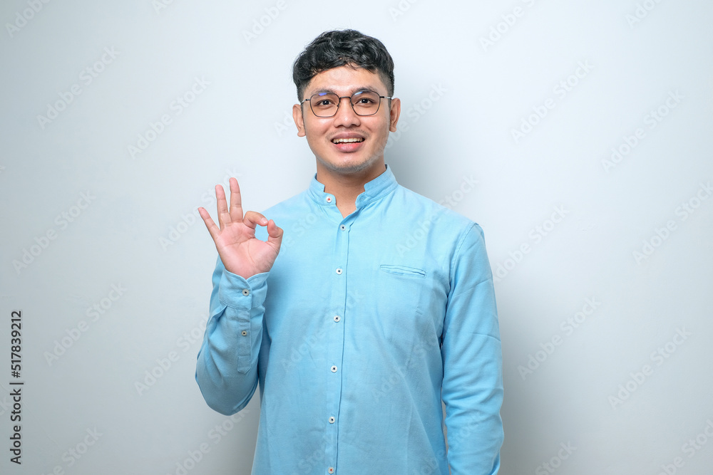 Young Asian man smiling and doing ok sign with fingers, excellent symbol Young Asian man smiling and doing ok sign with fingers, excellent symbol