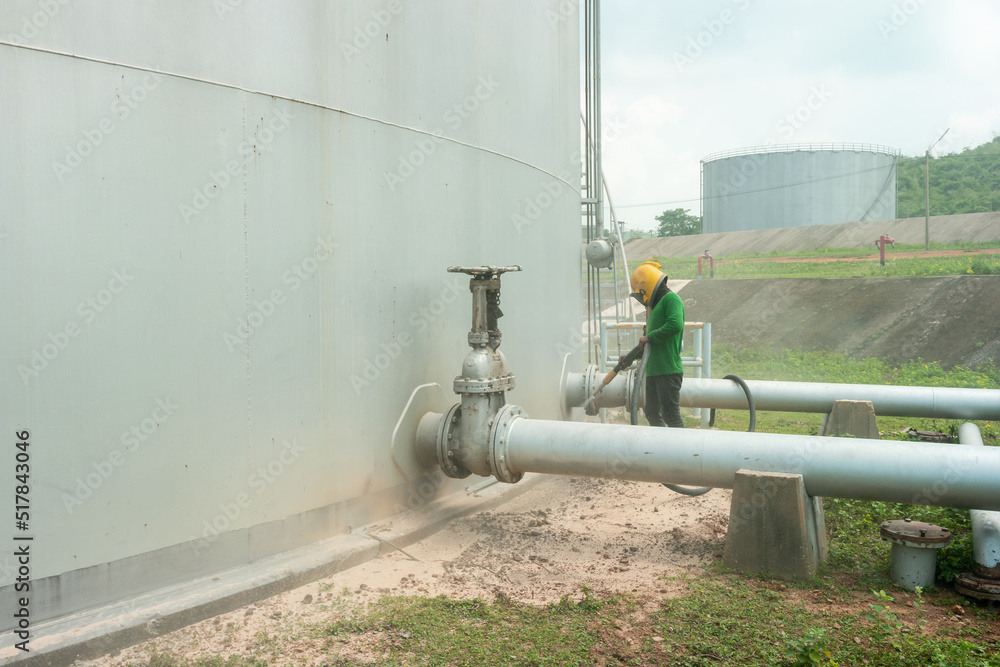 Man worker surface preparation of corrosion iron plate by sand blasting at fuel oil tank. Man worker surface preparation of corrosion iron plate by sand blasting at fuel oil tank.