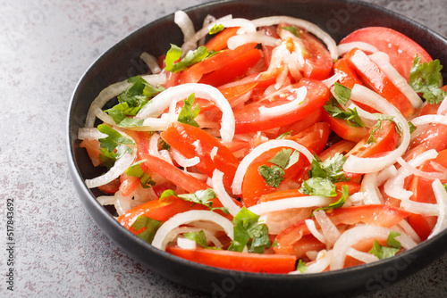 Concept healthy appetizer Fresh tomatoes with onion and spices closeup in the plate on the table. Horizontal