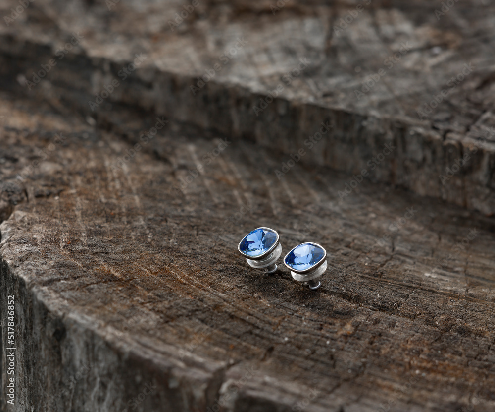 Silver stud earrings with blue cabochons is on an old stump Silver stud earrings with blue cabochons is on an old stump