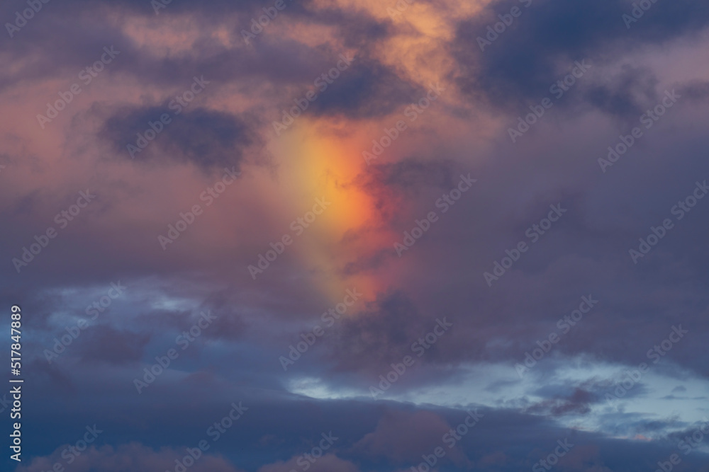 Rainbow in dramatic clouds after rain in the evening sky.