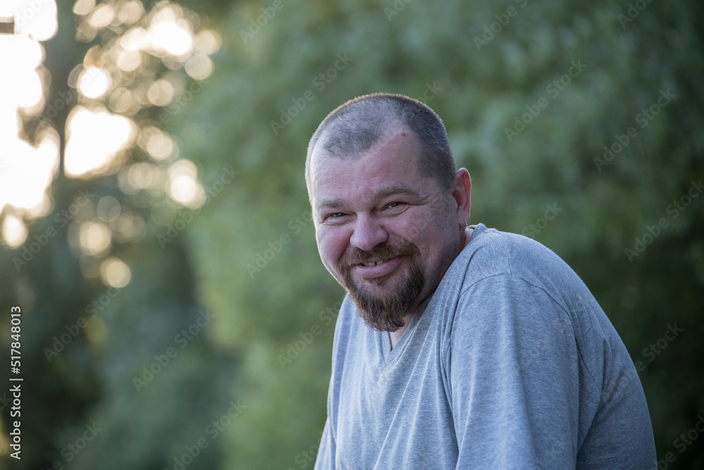 An adult man with a beard smiles, in nature. An adult man with a beard smiles, in nature.