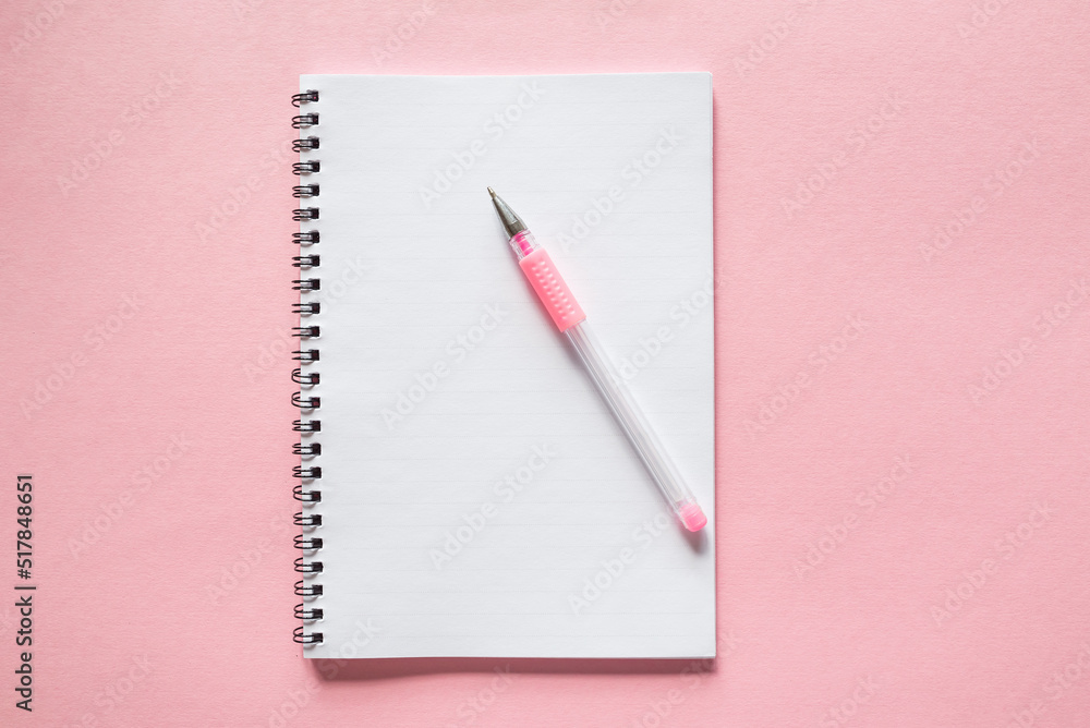 white notebook with a pen on a pink background. copy space. white notebook with a pen on a pink background. copy space.