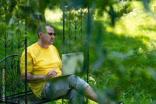senior man with laptop working outside in garden, green home office concept. © ako-photography