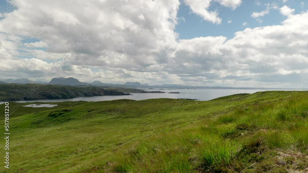 A wide landscape view of the mountains (suilven) and rocky coastline of North Scotland (Sutherland) with lush green grass and slowly moving clouds, filmed on Handa Island. A wide landscape view of the mountains (suilven) and rocky coastline of North Scotland (Sutherland) with lush green grass and slowly moving clouds, filmed on Handa Island.