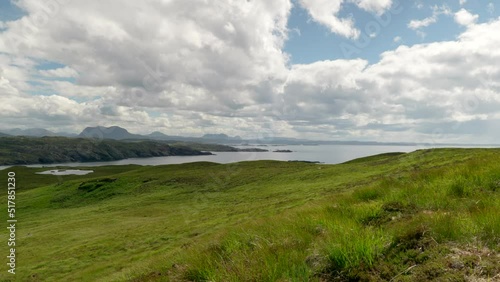 A wide landscape view of the mountains (suilven) and rocky coastline of North Scotland (Sutherland) with lush green grass and slowly moving clouds, filmed on Handa Island. photo