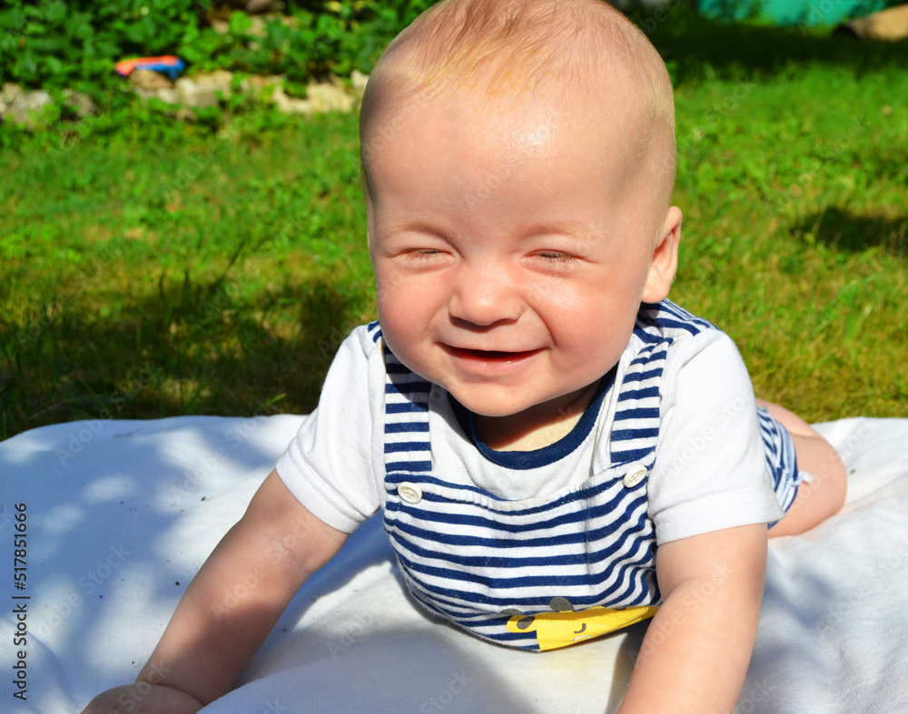 Happy baby squints his eyes from the sun Happy baby squints his eyes from the sun