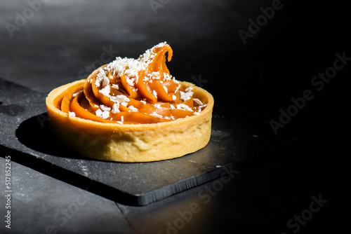 Detailed close up of a caramel tart with white chocolate flakes