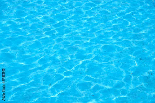 The wind makes the water ripple. Blue swimming pool reflecting the sun rippled. Rubbish at the bottom of the pool, dirty blue bottom of the pool.