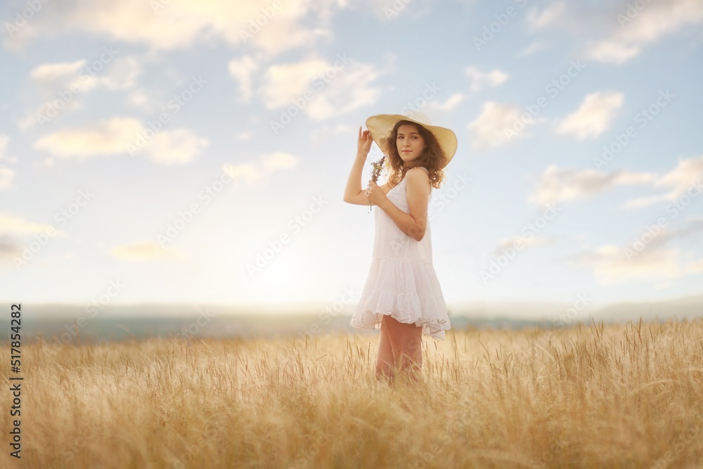 Woman in hat on the field with flowers on the field background Woman in hat on the field with flowers on the field background