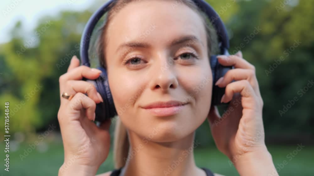 Beautiful dreamful positive pretty female athlete takes off headphones after listening to music looking to camera posing at sunset in nature outdoor. Woman. Motivation. Freedom. Enjoyment. Summer. Beautiful dreamful positive pretty female athlete takes off headphones after listening to music looking to camera posing at sunset in nature outdoor. Woman. Motivation. Freedom. Enjoyment. Summer.