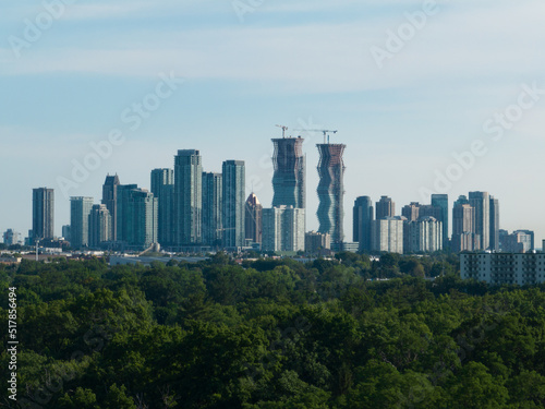 A modern cityscape skyline is seen on the horizon of a sunny day. New buildings and condos are under construction. © The Bold Bureau