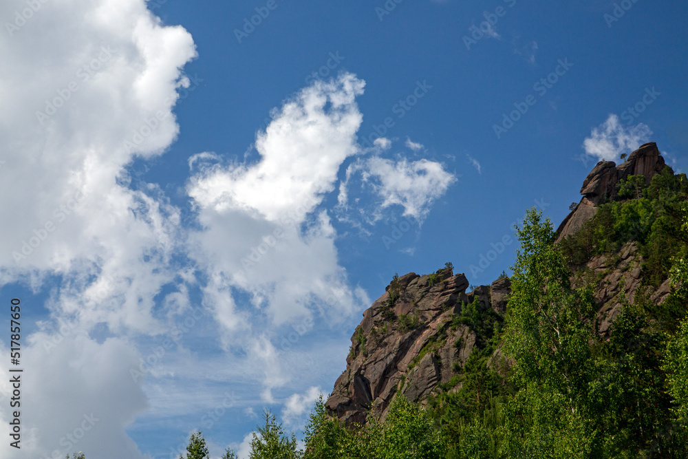 Mountain top with rocks and forest under a blue sky with white clouds. Mountain top with rocks and forest under a blue sky with white clouds.