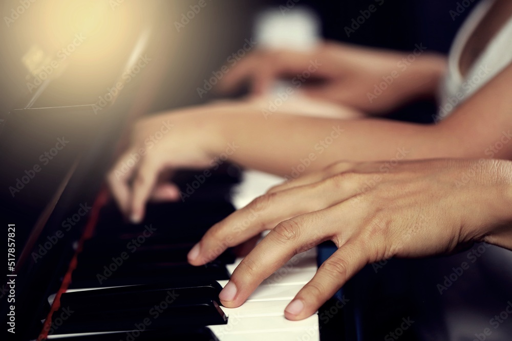 Fototapeta premium Select the focus on the piano trainer fingers and piano keys to play the piano. There are musical instruments for concerts or music lessons. Close-up of child musicians playing piano on stage