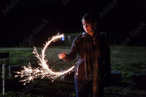 Teen girl spinning a sparkler at night photo