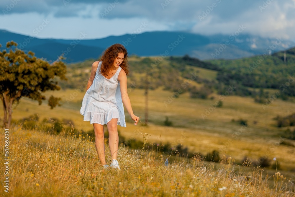 Woman in the field with flowers on landscape background