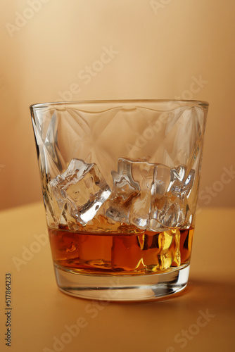 crystal glass with ice and whiskey with reflection on dark background seen in a swooping view
