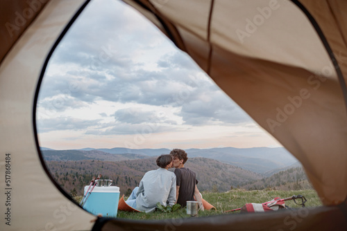 View from inside tent on beautiful landscape of mountains and couple kissing. Love and travel. 