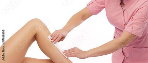 Professional worker is removing hair from young and beautiful female body and legs with hot wax. Girl has a beauty treatment procedure. Depilation  epilation and health care concepts.