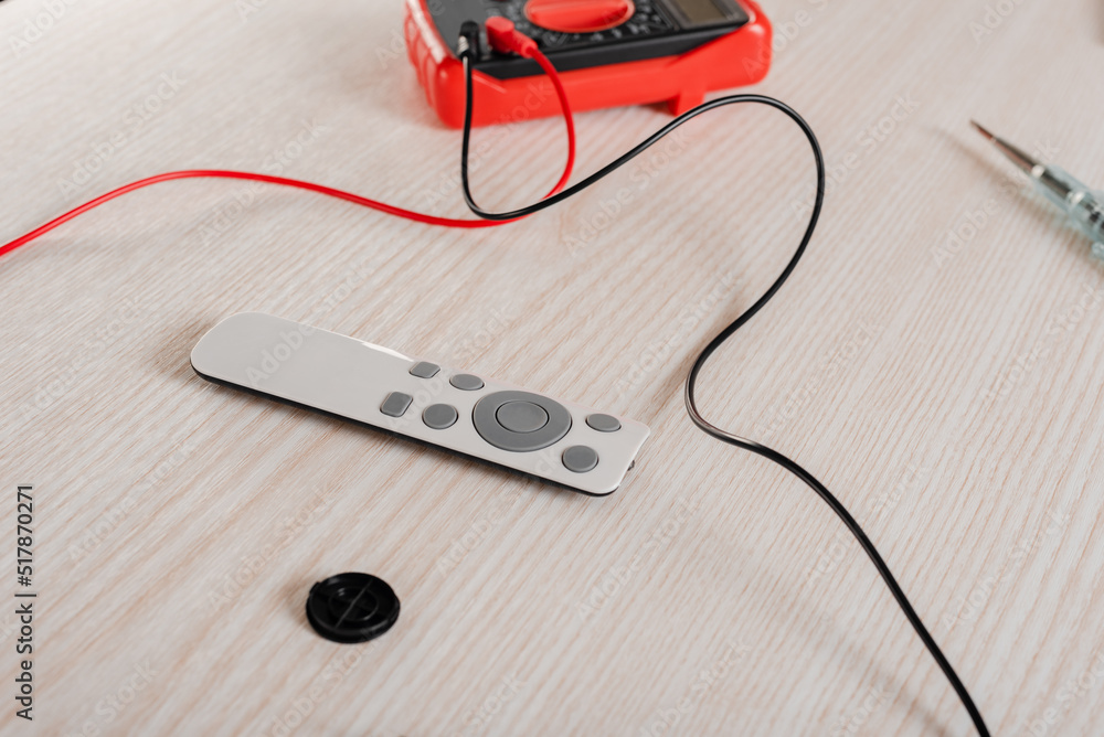 Electric tester multimeter with remote control on wooden background Electric tester multimeter with remote control on wooden background