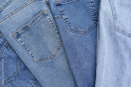 Lots of jeans pants in a stack. Denim background.