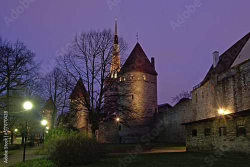 Nocturnal view on artificially lighted medieval city walls with fortified towers in Tallinn, Estonia, view from the park 