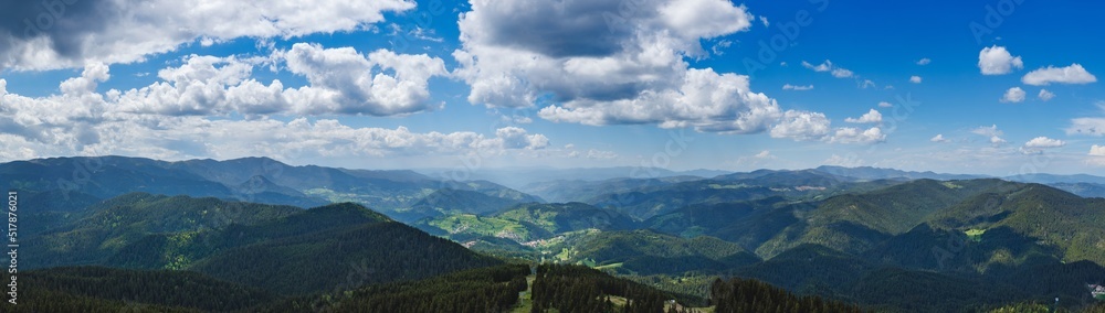 Naklejka premium Panorama on mountain valley sheltered by vegetation and forests with village of Smolyan with meadows where sheep graze