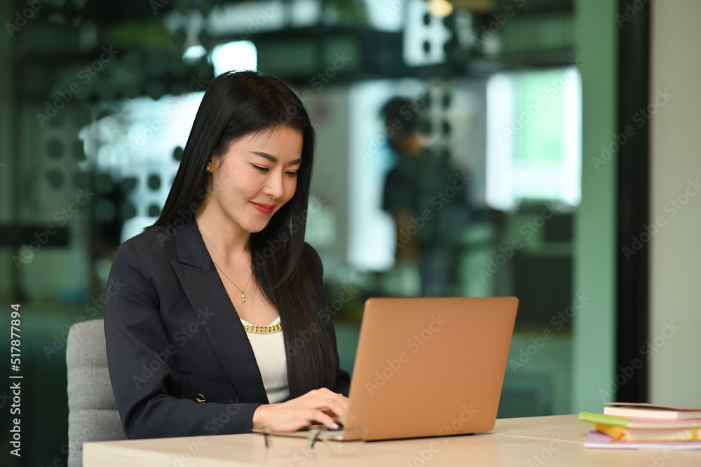 Millennial female entrepreneur using laptop, working on research project in her personal office Millennial female entrepreneur using laptop, working on research project in her personal office