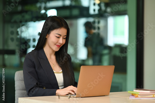 Millennial female entrepreneur using laptop, working on research project in her personal office