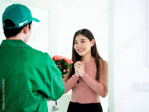 Asian pretty young girl surprise and impress when see pink rose bouquet from delivery man at the white color apartment