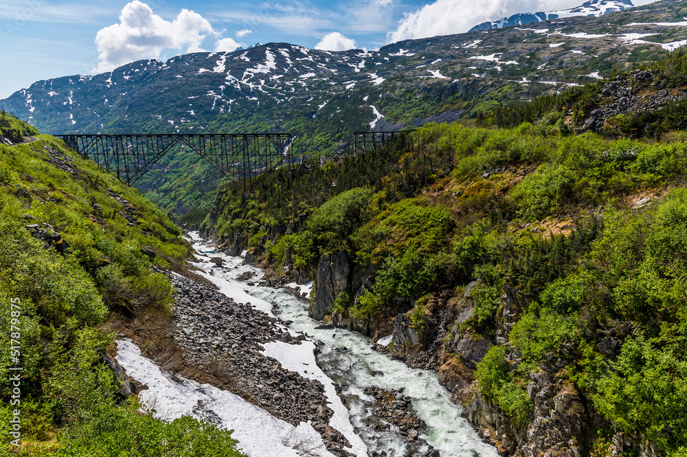 A view down a ravine towards a derelict bridge at the highest point of the White Pass near Skagway, Alaska in summertime