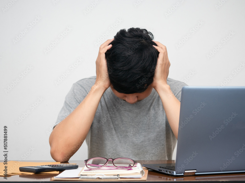 Depressed man holding head at working desk Depressed man holding head at working desk