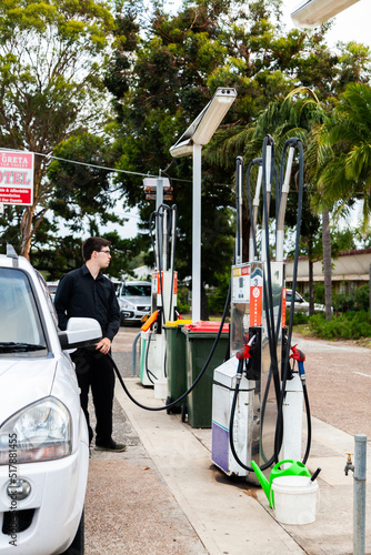 Young man filling car up with petrol at country service station in Australian town