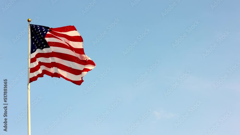 Beautiful American flag waving in the wind, with vibrant red white and blue colors lit by the sun, against blue sky for copy space. Beautiful American flag waving in the wind, with vibrant red white and blue colors lit by the sun, against blue sky for copy space.