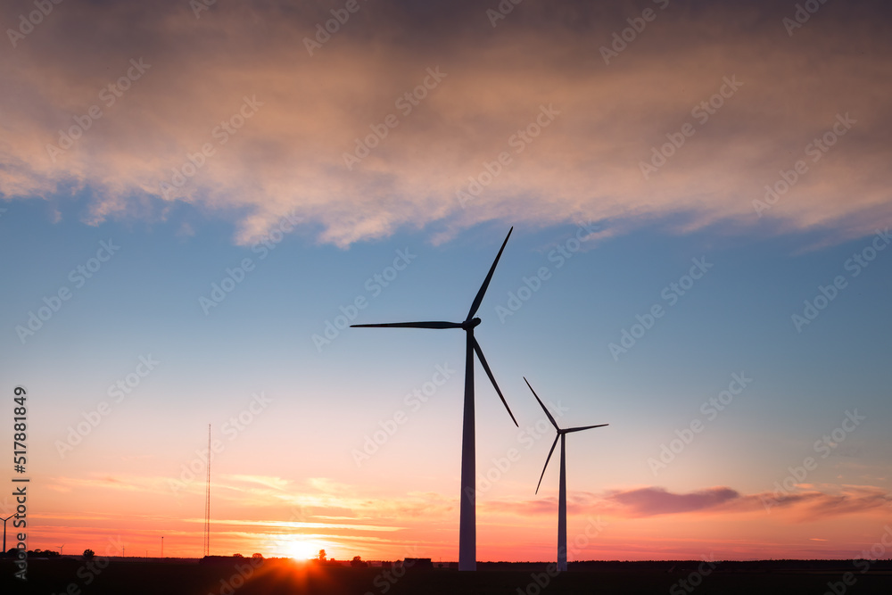 Fototapeta premium Wind farm in agricultural landscape, sunset wind turbines producing electricity, wind energy is renewable energy, clean, renewable energy source, wind turbines against the setting sun